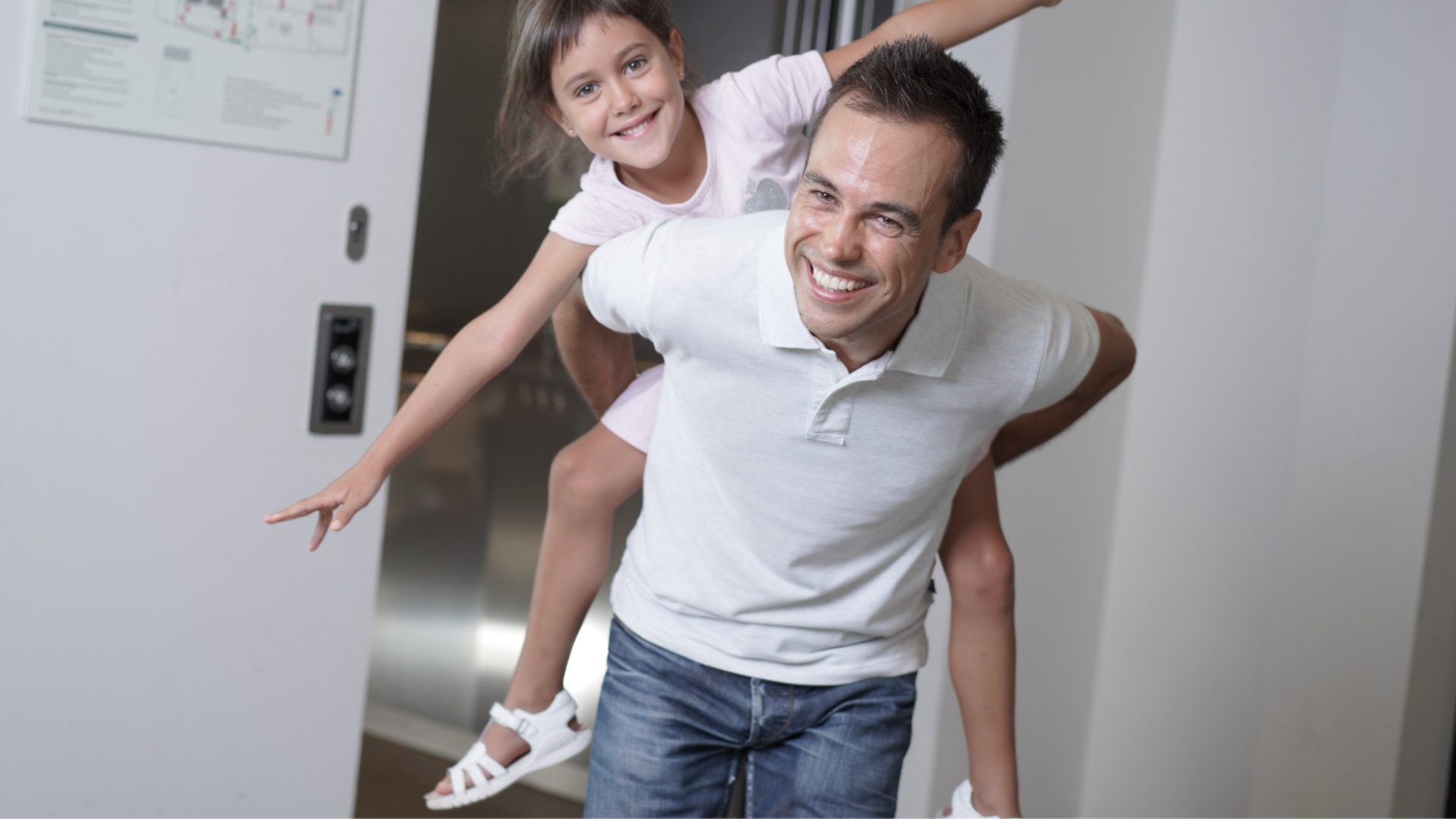 Padre con figlia alle spalle mentre esce da un ascensore Orona