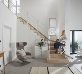 Señora subiendo las escaleras de su casa en una silla salvaescaleras de Orona