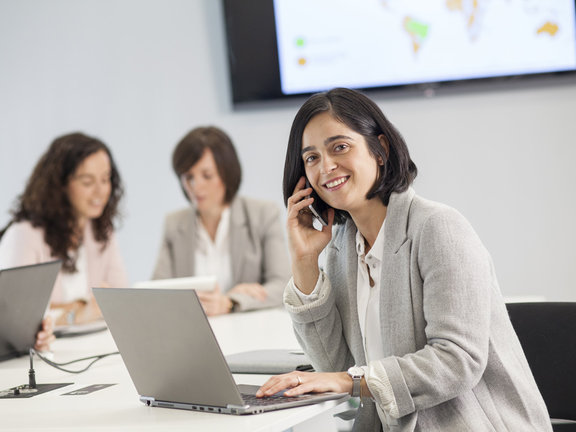 Donna che parla al telefono e lavora al portatile