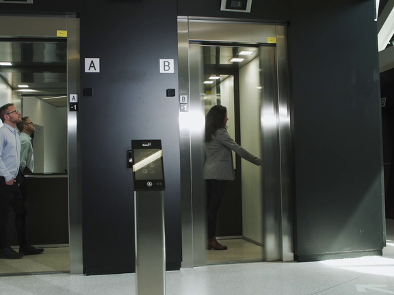 «Duas pessoas em dois elevadores num escritório»