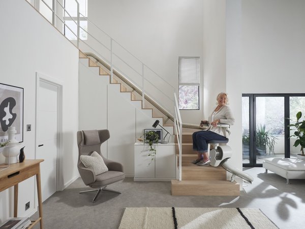 Woman travelling up the stairs of her house in an Orona stairlift